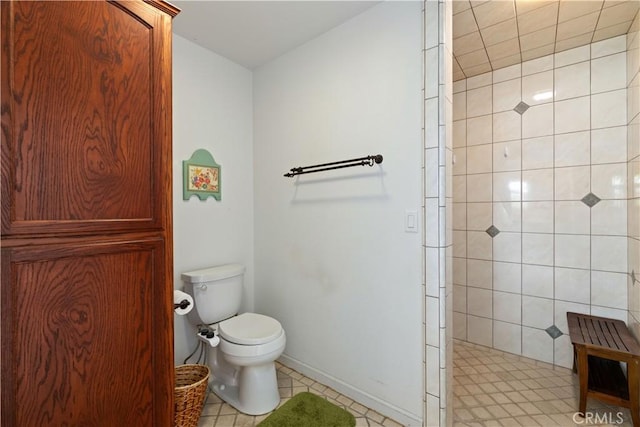 bathroom featuring a tile shower, tile patterned flooring, and toilet