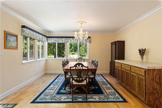 dining room with light wood-type flooring, crown molding, and a notable chandelier