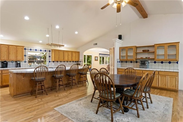 dining area featuring beam ceiling, ceiling fan, high vaulted ceiling, and light wood-type flooring