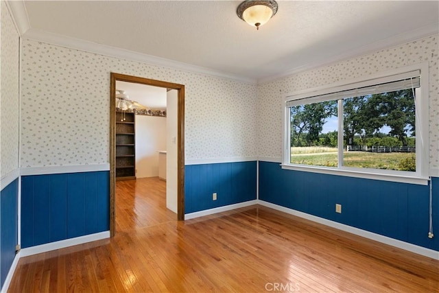 unfurnished room featuring hardwood / wood-style flooring, wood walls, and ornamental molding