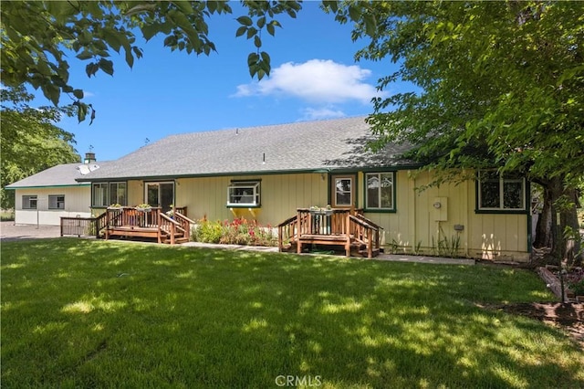 rear view of house featuring a lawn and a wooden deck