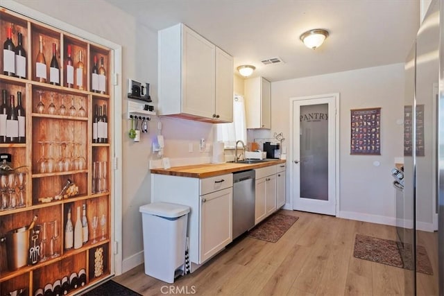 kitchen with white cabinetry, sink, stainless steel appliances, wooden counters, and light wood-type flooring