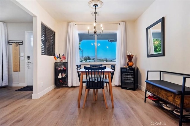 dining room featuring wine cooler, a chandelier, and light hardwood / wood-style floors