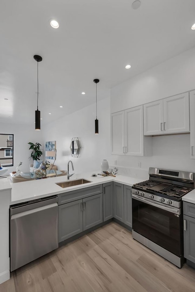 kitchen with appliances with stainless steel finishes, gray cabinetry, pendant lighting, and sink