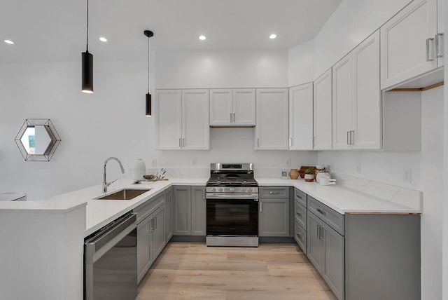 kitchen featuring decorative light fixtures, black dishwasher, sink, stainless steel gas range oven, and gray cabinetry