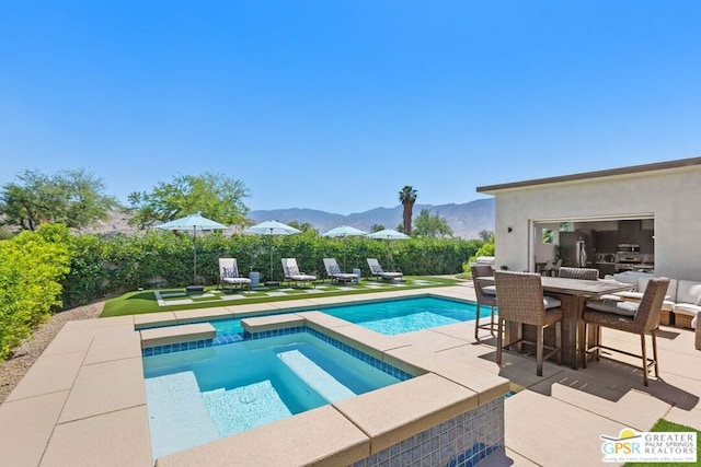 view of swimming pool with a mountain view, a patio, and an in ground hot tub