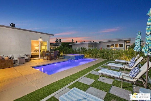 pool at dusk with pool water feature, a patio area, and an in ground hot tub