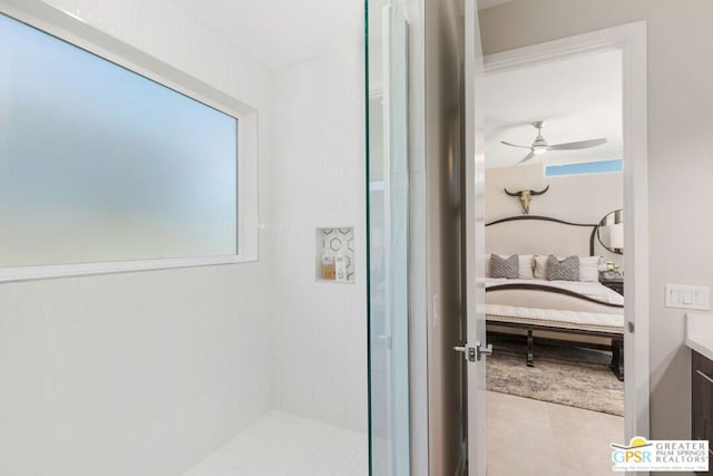 bathroom featuring tile patterned flooring, a tile shower, vanity, and ceiling fan