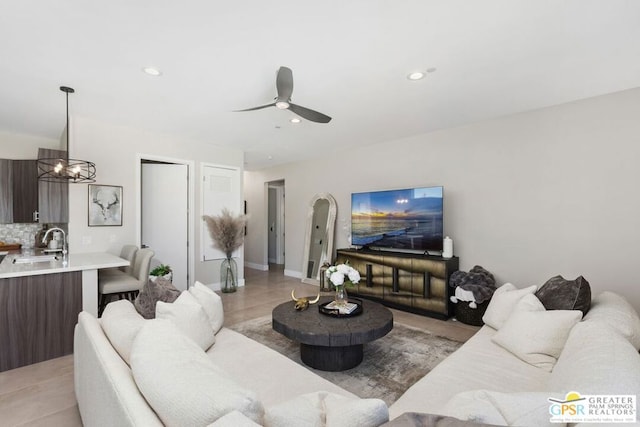 living room with light tile patterned flooring, ceiling fan with notable chandelier, and sink