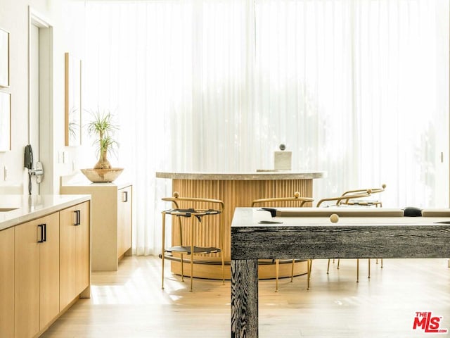 bar featuring light brown cabinets and light wood-type flooring