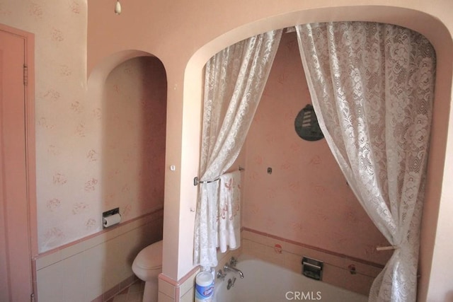 bathroom featuring toilet and a tub to relax in