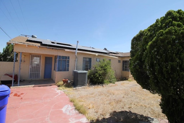 back of house with central AC and solar panels