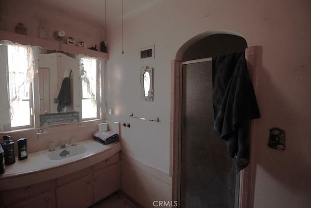 bathroom featuring vanity, backsplash, and walk in shower