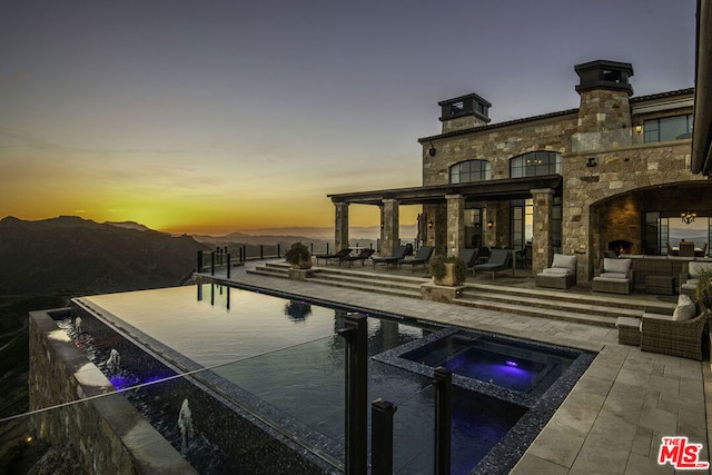 pool at dusk featuring a patio and outdoor lounge area