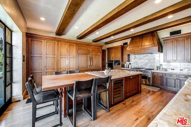 kitchen featuring high end appliances, custom range hood, light hardwood / wood-style floors, and beverage cooler