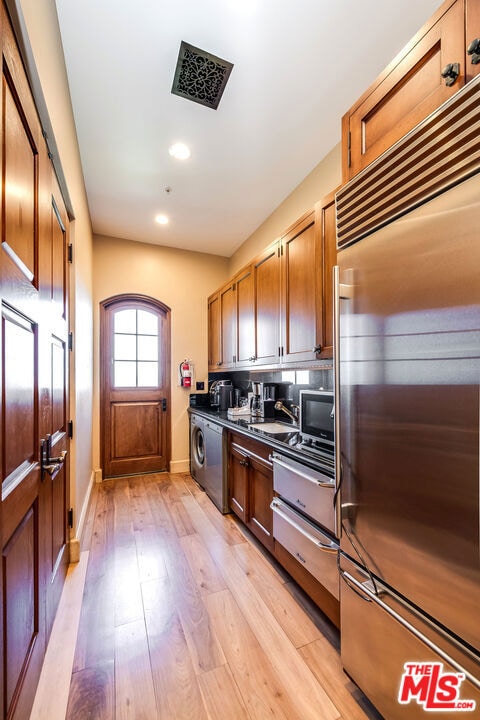 kitchen featuring light hardwood / wood-style flooring, backsplash, washer / dryer, and built in refrigerator