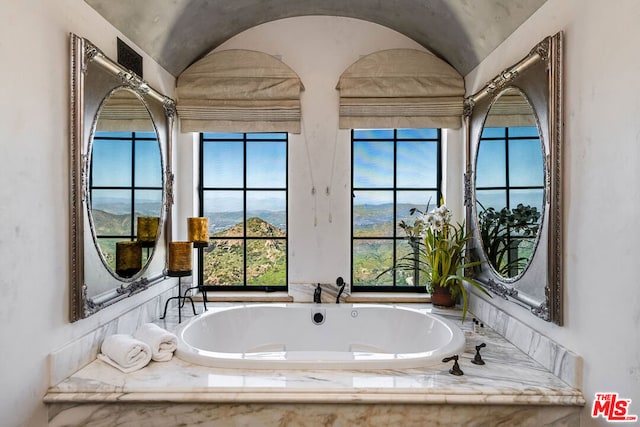 bathroom with a relaxing tiled bath and lofted ceiling