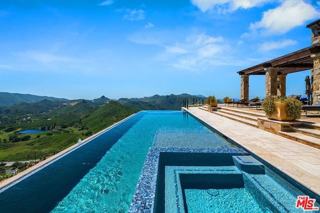 view of swimming pool featuring an in ground hot tub and a mountain view