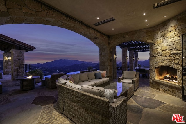 patio terrace at dusk with an outdoor living space with a fireplace and a mountain view