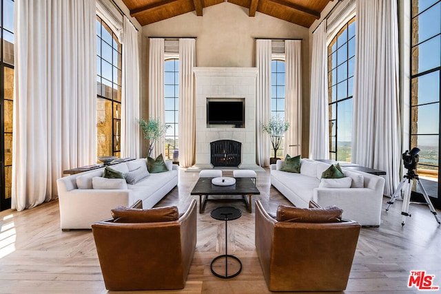 living room with high vaulted ceiling, wooden ceiling, beam ceiling, and a tile fireplace