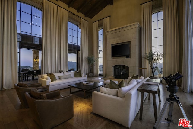 living room featuring beam ceiling, high vaulted ceiling, and a tile fireplace