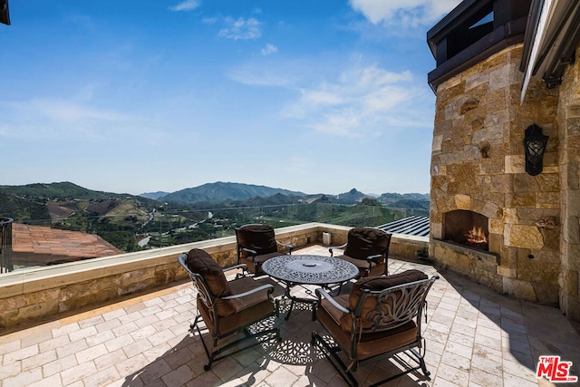 view of terrace with a mountain view and an outdoor stone fireplace