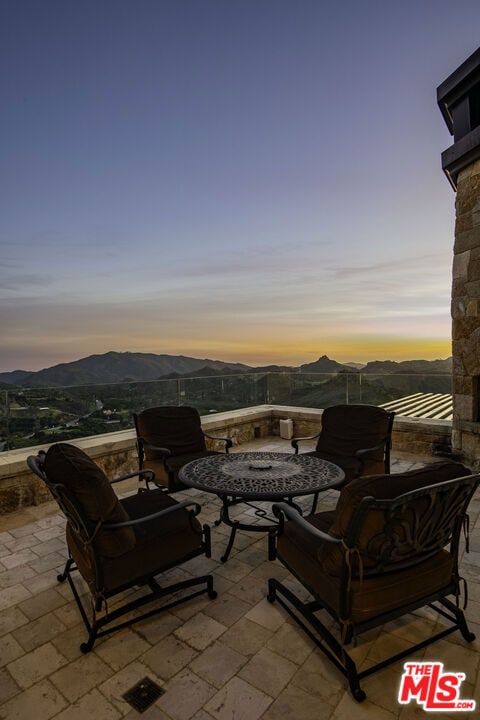 patio terrace at dusk featuring a mountain view