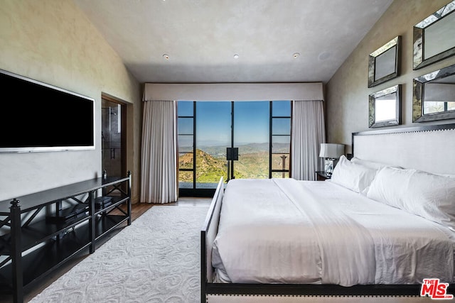 bedroom with vaulted ceiling, hardwood / wood-style flooring, and access to outside