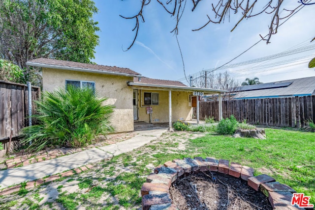 back of property featuring a yard, a patio, and solar panels