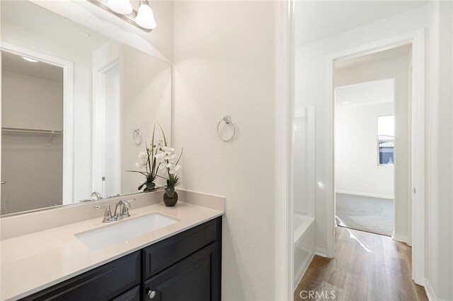 bathroom with wood-type flooring, a tub to relax in, and vanity