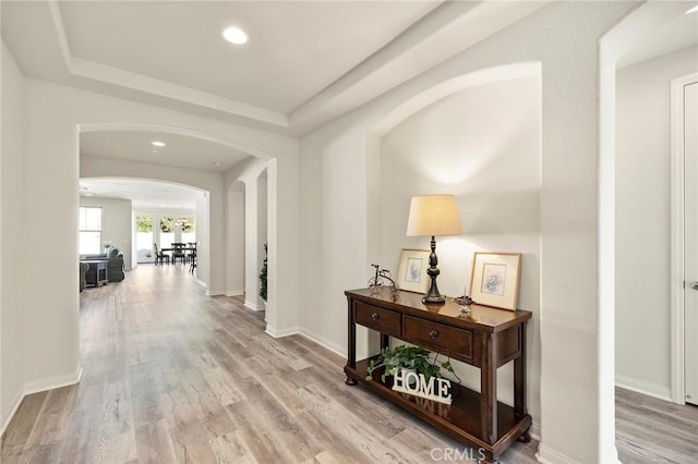 hallway with hardwood / wood-style flooring and a tray ceiling