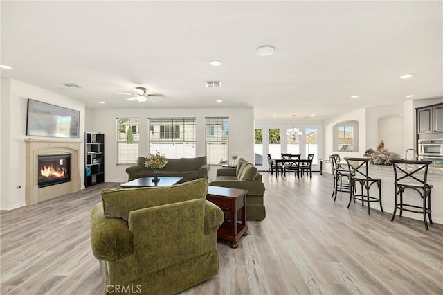 living room with ceiling fan, light wood-type flooring, and sink