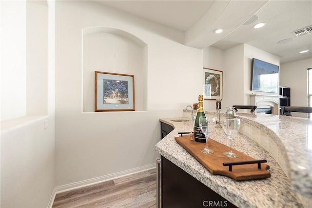 interior space with sink, light hardwood / wood-style flooring, and light stone countertops