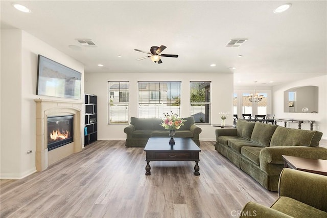 living room with ceiling fan with notable chandelier and light wood-type flooring