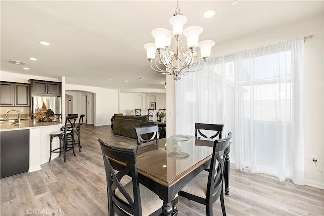 dining room featuring sink, an inviting chandelier, and light hardwood / wood-style flooring