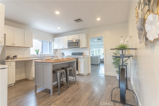 kitchen featuring white cabinets, wood-type flooring, appliances with stainless steel finishes, and a center island