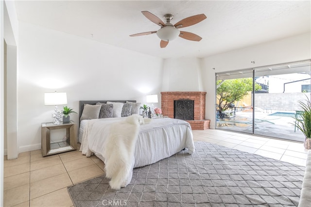 bedroom featuring light tile floors, ceiling fan, a fireplace, and access to outside