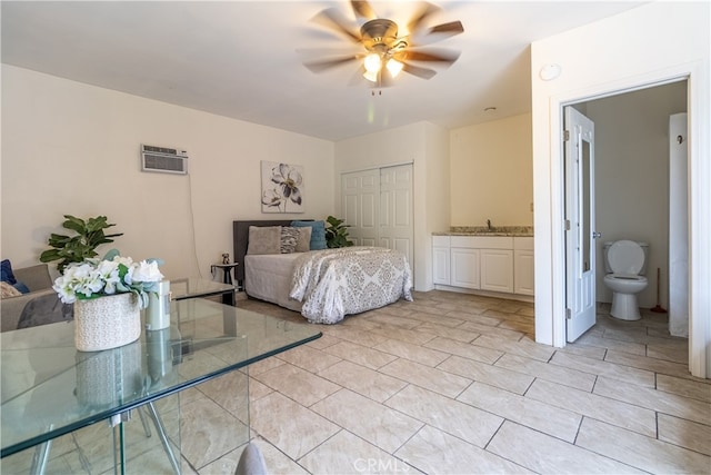 unfurnished bedroom featuring ceiling fan, a closet, ensuite bath, a wall mounted air conditioner, and light tile floors