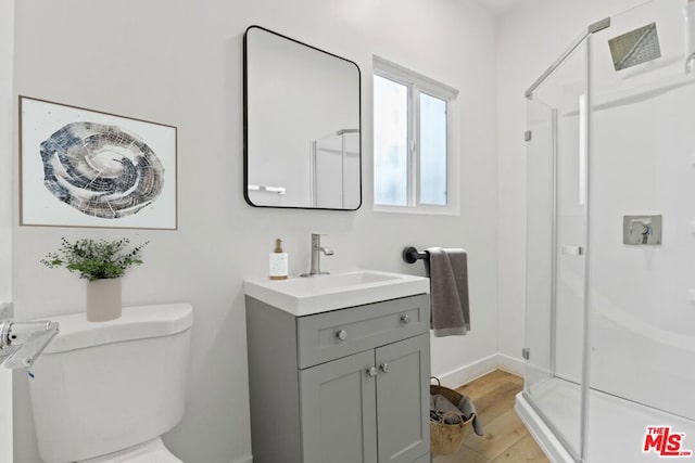 bathroom featuring an enclosed shower, wood-type flooring, toilet, and vanity