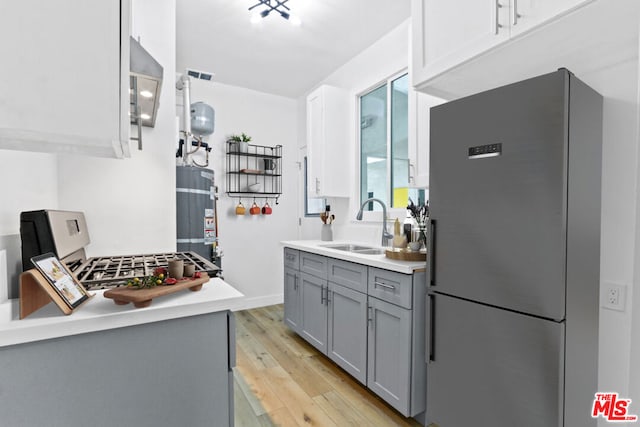 kitchen with light hardwood / wood-style floors, gray cabinetry, water heater, sink, and refrigerator