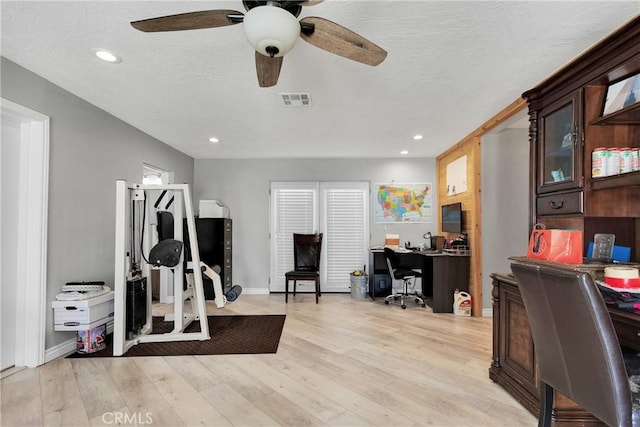 workout area featuring ceiling fan, a textured ceiling, and light wood-type flooring