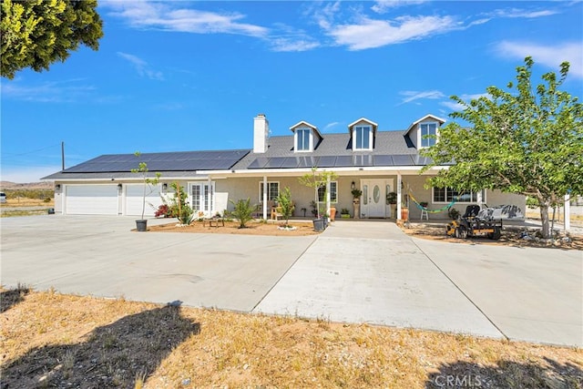 view of front facade featuring a garage, a porch, and solar panels