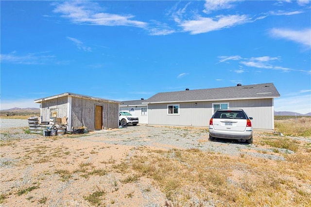 back of property with a mountain view and an outdoor structure