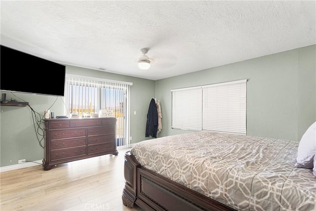 bedroom featuring ceiling fan, light hardwood / wood-style floors, and a textured ceiling