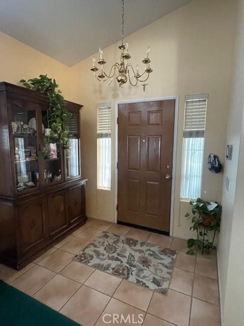 tiled foyer entrance with vaulted ceiling and an inviting chandelier