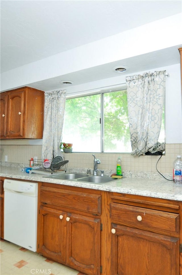 kitchen featuring light tile patterned floors, dishwasher, backsplash, and sink