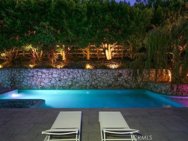 pool at night with a patio area