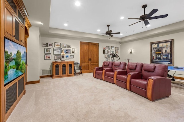 cinema room with light colored carpet, a raised ceiling, and ceiling fan