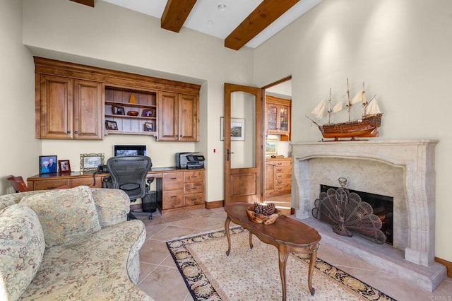 tiled home office with built in desk, beamed ceiling, and a high end fireplace