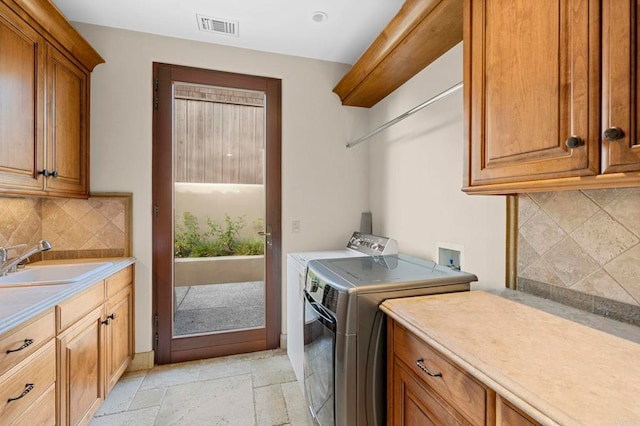 washroom with sink, washer and dryer, and cabinets